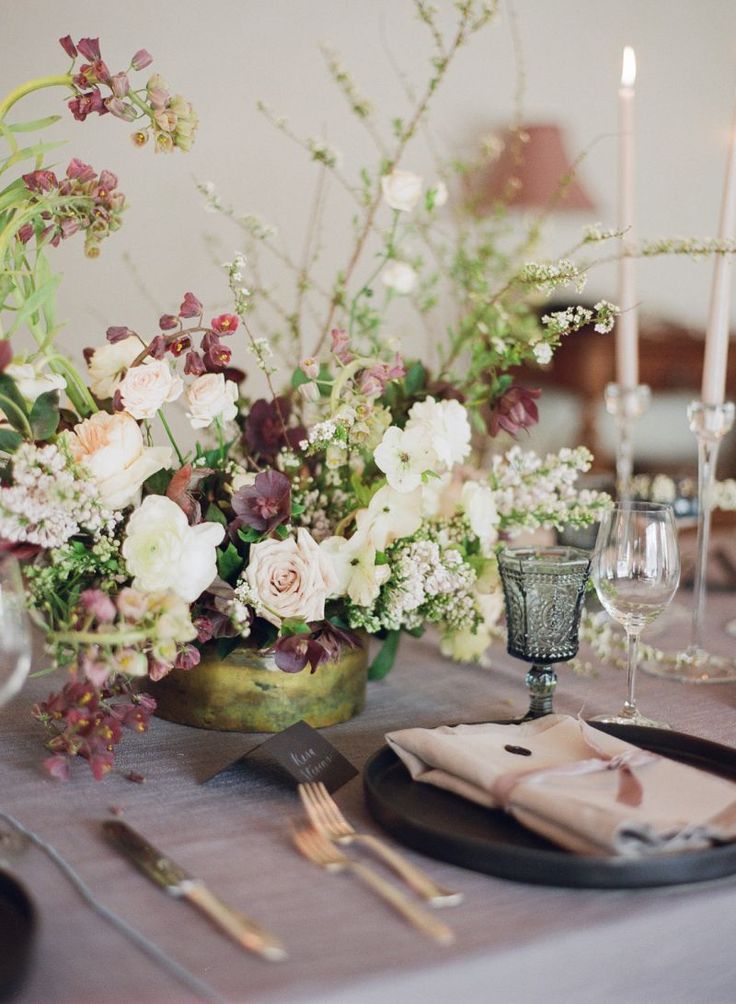 the table is set with silverware, plates and flowers in vases on it