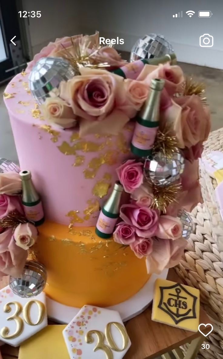 a pink cake with flowers and decorations on top is surrounded by gold foil, confetti and numbers