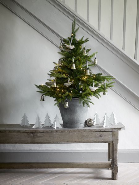 a potted christmas tree sitting on top of a table next to a stair case