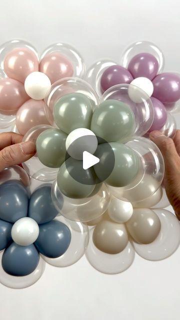 two hands holding balloons in the shape of flowers, and another hand reaching for them