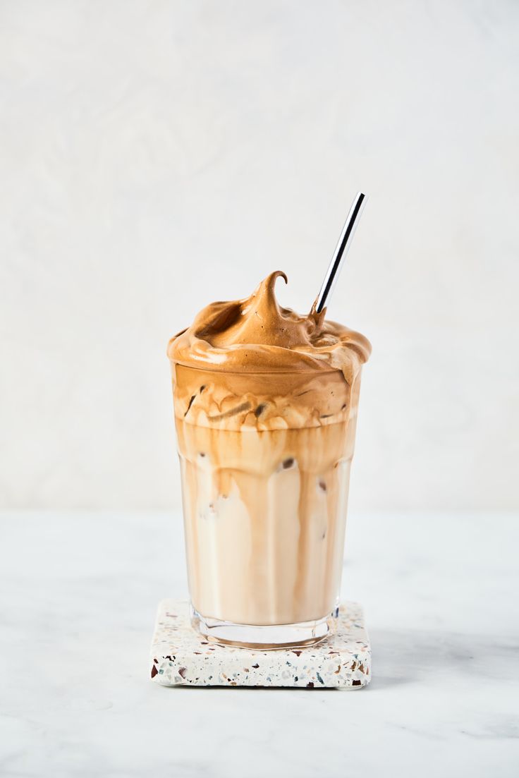 an iced coffee drink with whipped cream and chocolate toppings on a marble table top