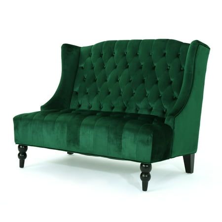 a green velvet couch with black legs and buttons on the back, sitting in front of a white background