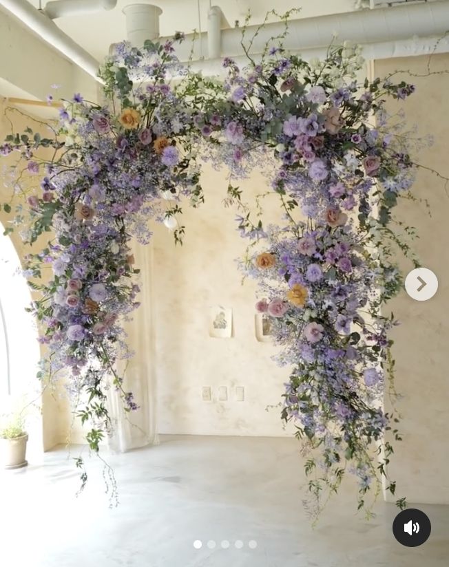 an arch made out of flowers and vines in the middle of a room with white walls