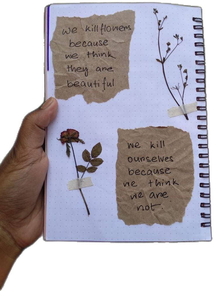 someone is holding up a notebook with some writing on it and there are flowers in the pages