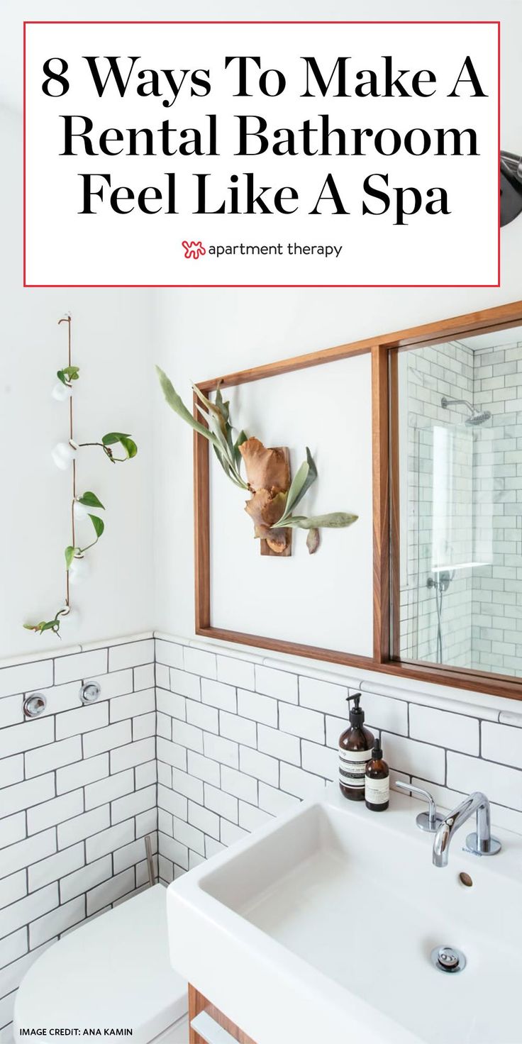 a bathroom with white tile and wood accents, including a large mirror above the sink