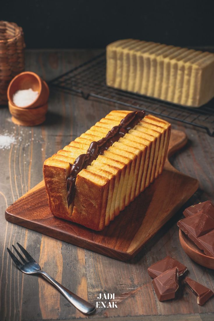 a loaf of bread with chocolate spread on it sitting on top of a wooden cutting board