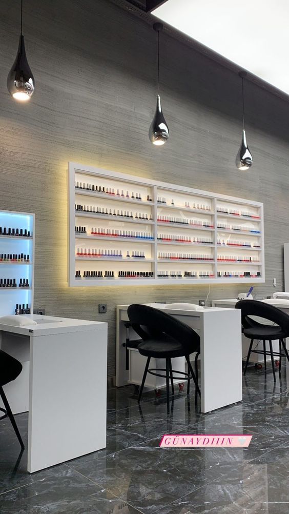 the interior of a nail salon with several tables and stools, lights hanging from the ceiling