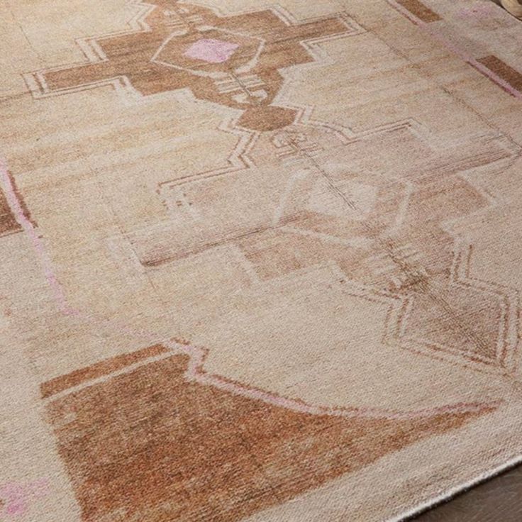 an area rug with various designs on it and a wooden table in the background,