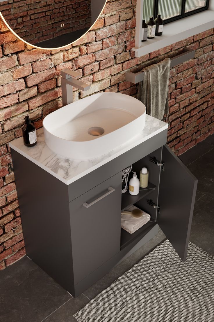 a bathroom sink sitting under a mirror next to a brick wall