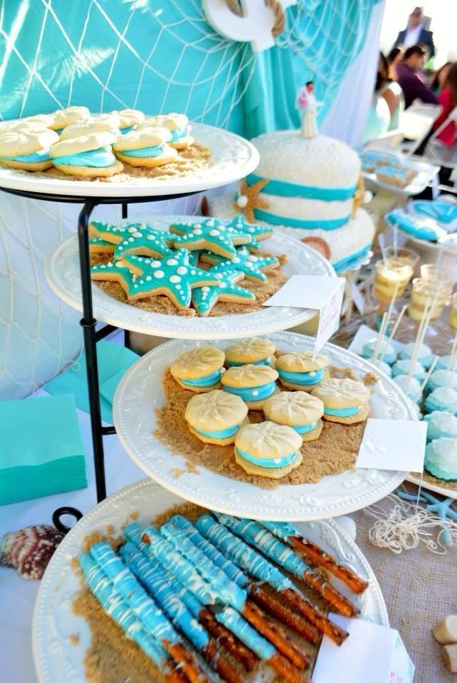 desserts are displayed on three tiered trays at a beach themed birthday party