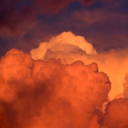 an airplane is flying through the clouds at sunset