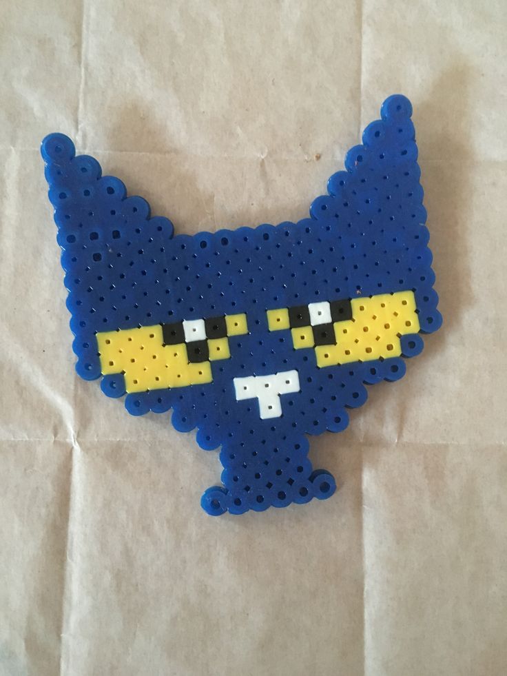 a blue and yellow cat made out of perler beads on top of a piece of paper