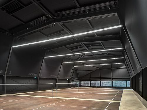 an empty tennis court with lights on the ceiling