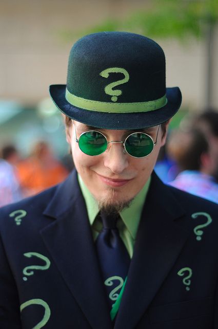 a man wearing green glasses and a top hat with question marks on it's side