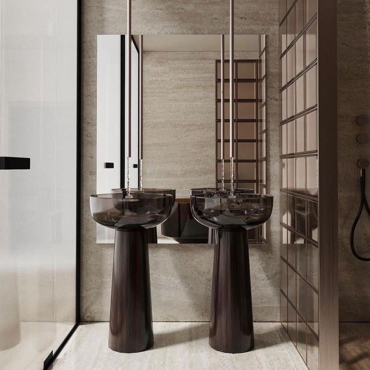 two black pedestal sinks in a bathroom next to a walk in shower and sink with mirrors on the wall