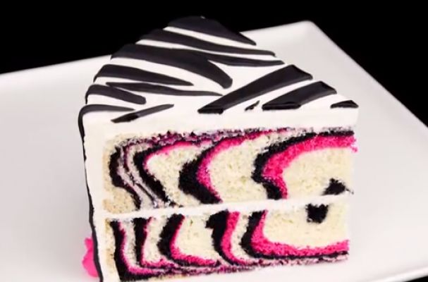 a slice of zebra print cake on a white plate with pink and black icing