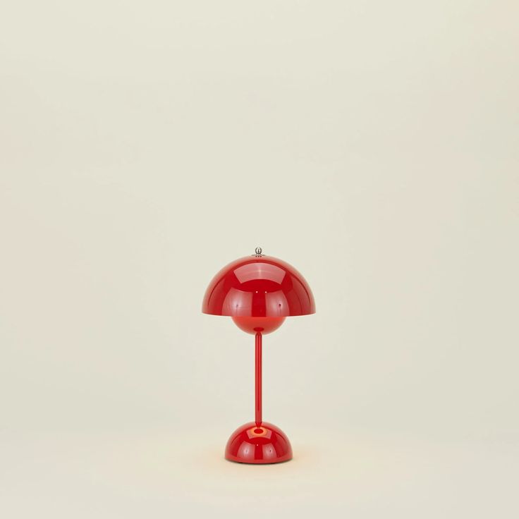 a red table lamp sitting on top of a white floor