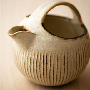 a white vase sitting on top of a wooden table