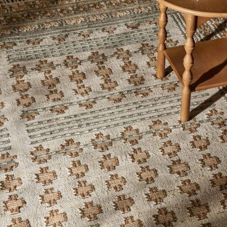 a wooden chair sitting next to a rug on top of a carpet covered floor in a living room