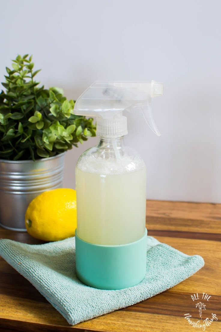 a bottle of soap sitting on top of a wooden table next to a potted plant