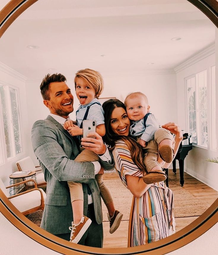 a man and woman taking a selfie with their children in front of a mirror