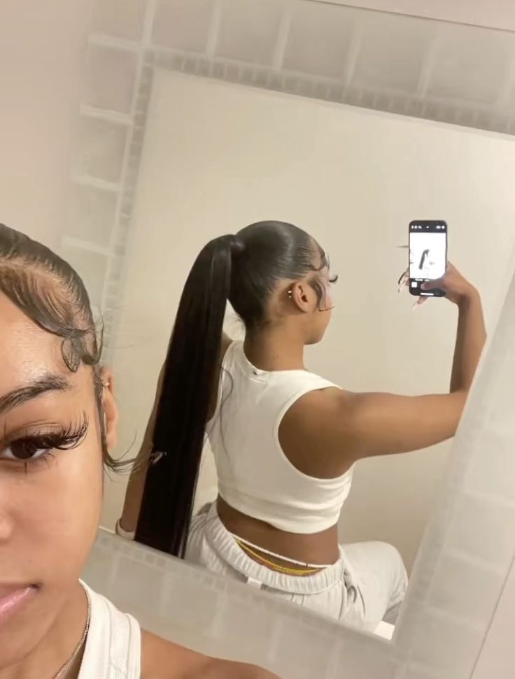 a woman taking a selfie in front of a mirror with her hair pulled back