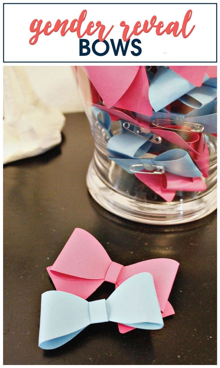 two paper bows sitting on top of a table next to a glass vase filled with pink and blue paper