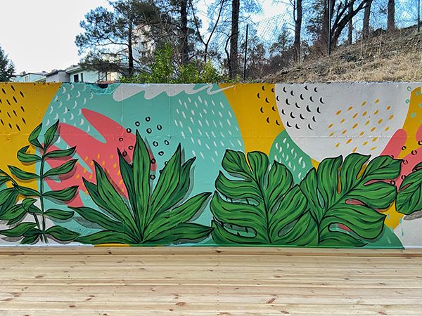 a skateboarder doing a trick in front of a colorful mural on the side of a wall