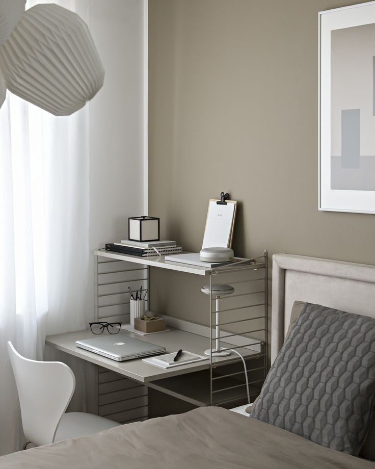 a bedroom with a bed, desk and chair next to a window in the corner