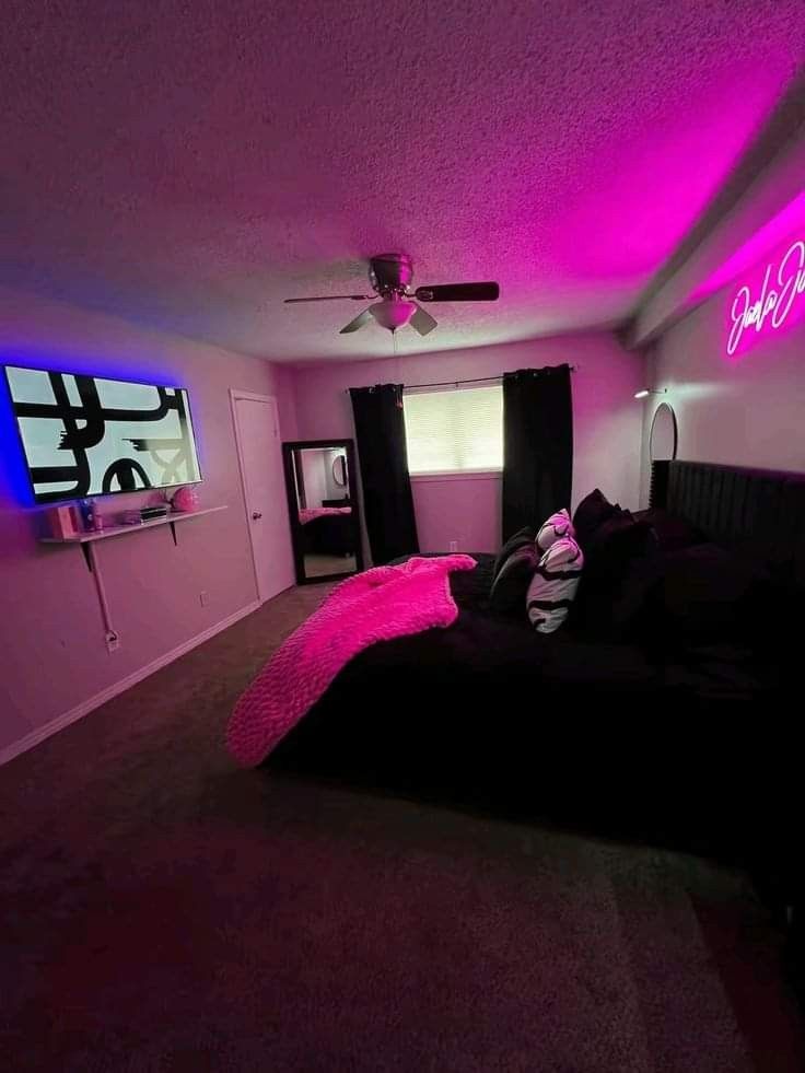 a bedroom with purple lighting and black furniture