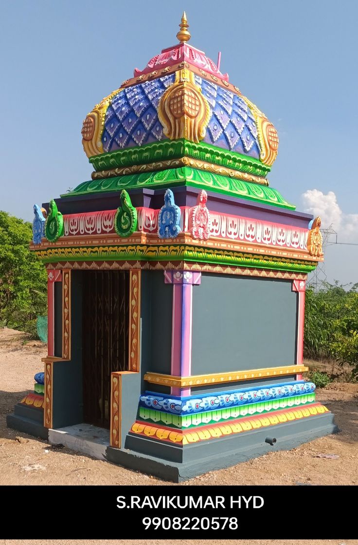 a colorfully painted gazebo sitting on top of a dirt field with trees in the background