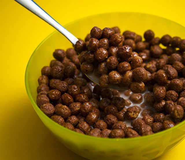 a green bowl filled with cereal on top of a yellow table