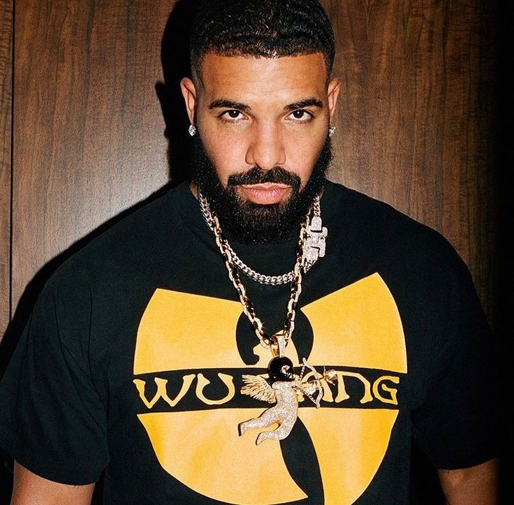 a man with a beard wearing a black t - shirt and gold chain around his neck