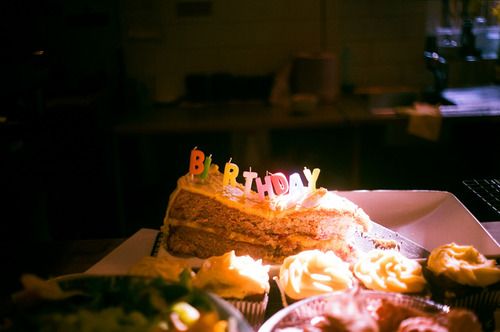 a birthday cake sitting on top of a table next to cupcakes and other food