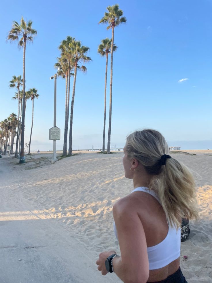 a woman running on the beach with palm trees in the background