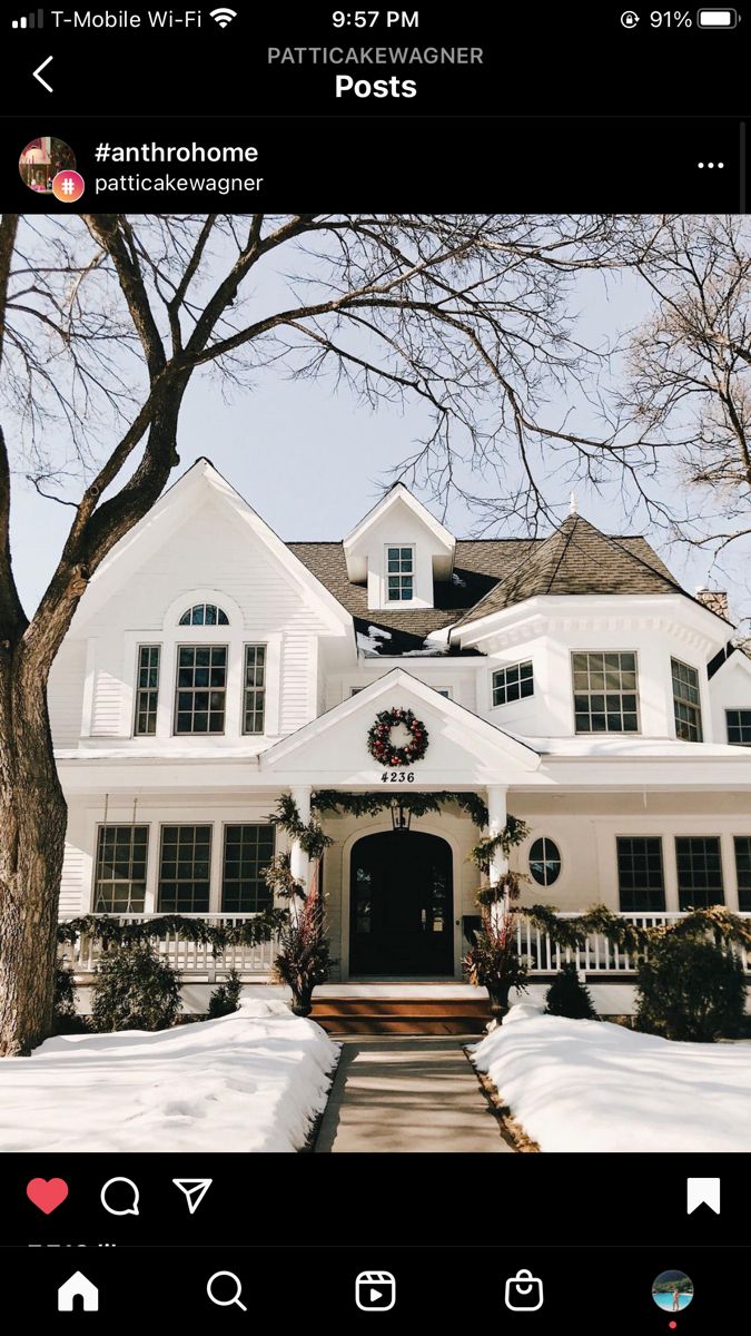 a white house with lots of snow on the ground and trees in front of it