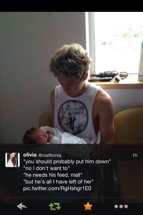 a man holding a baby in his arms while wearing a tank top with the words second child on it