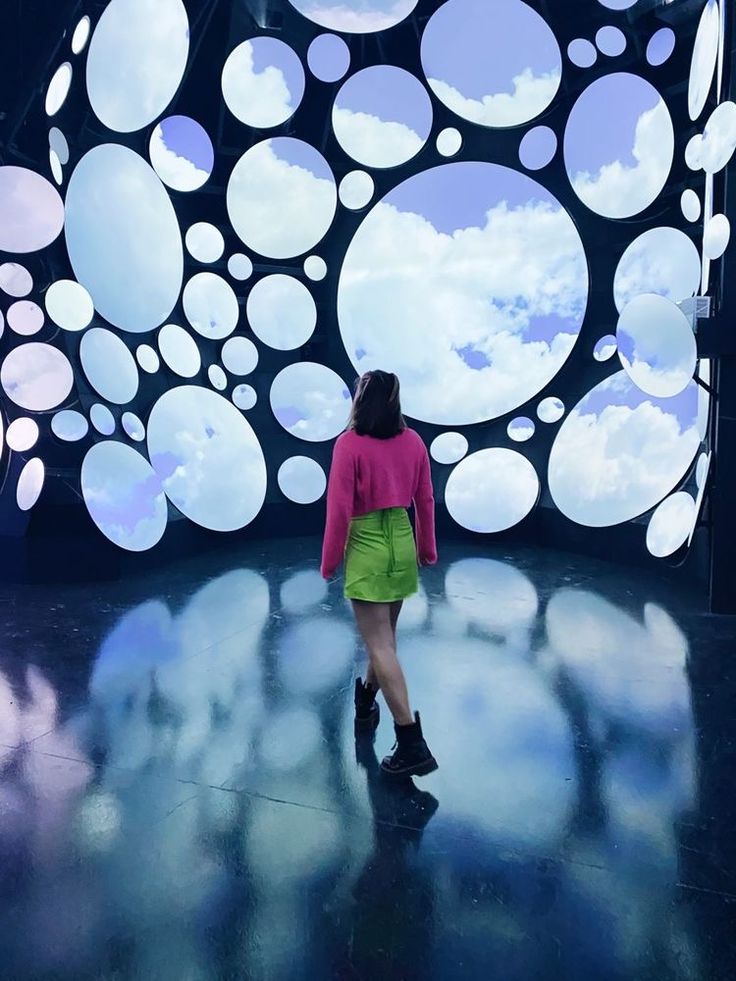 a woman is walking in front of an art installation