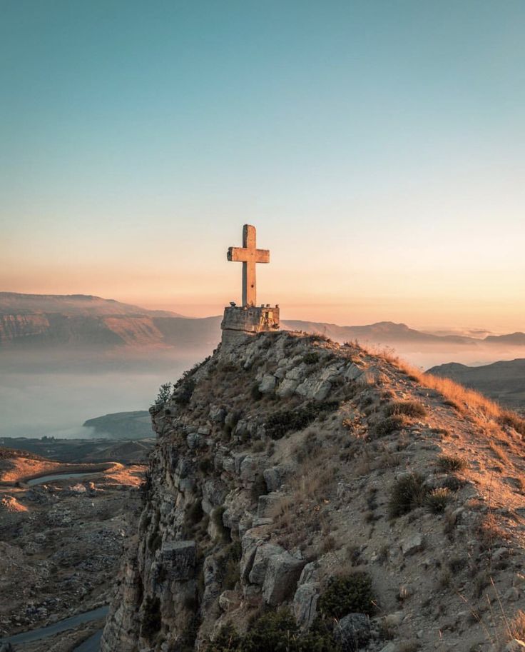 a cross on top of a hill with fog in the background