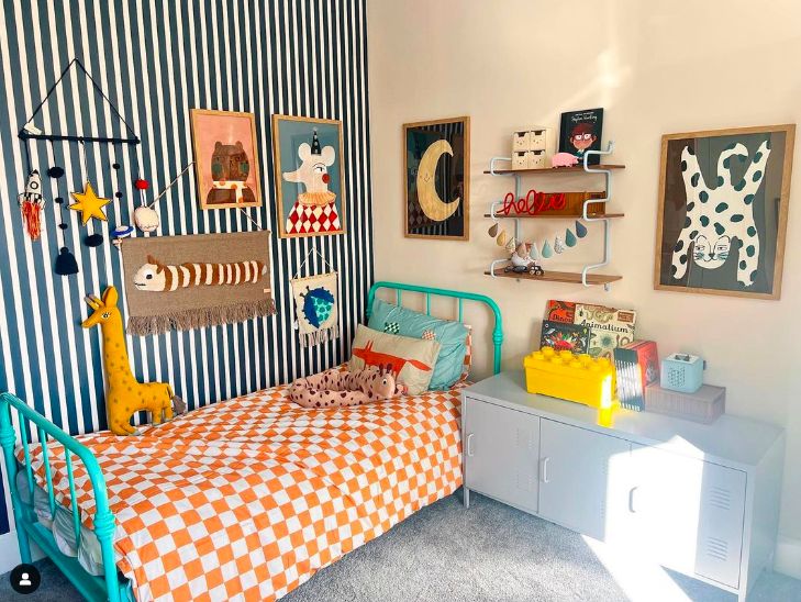 a child's bedroom with blue and white stripes on the walls, an orange checkered bedspread