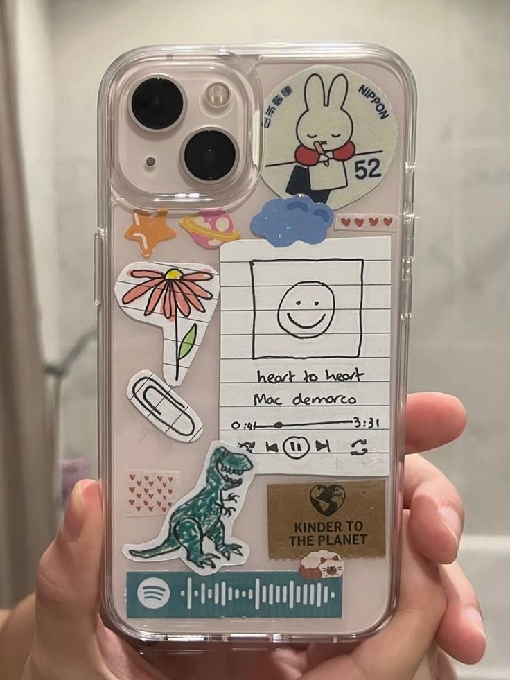 someone is holding up their phone case with stickers on it and there are other things in the back