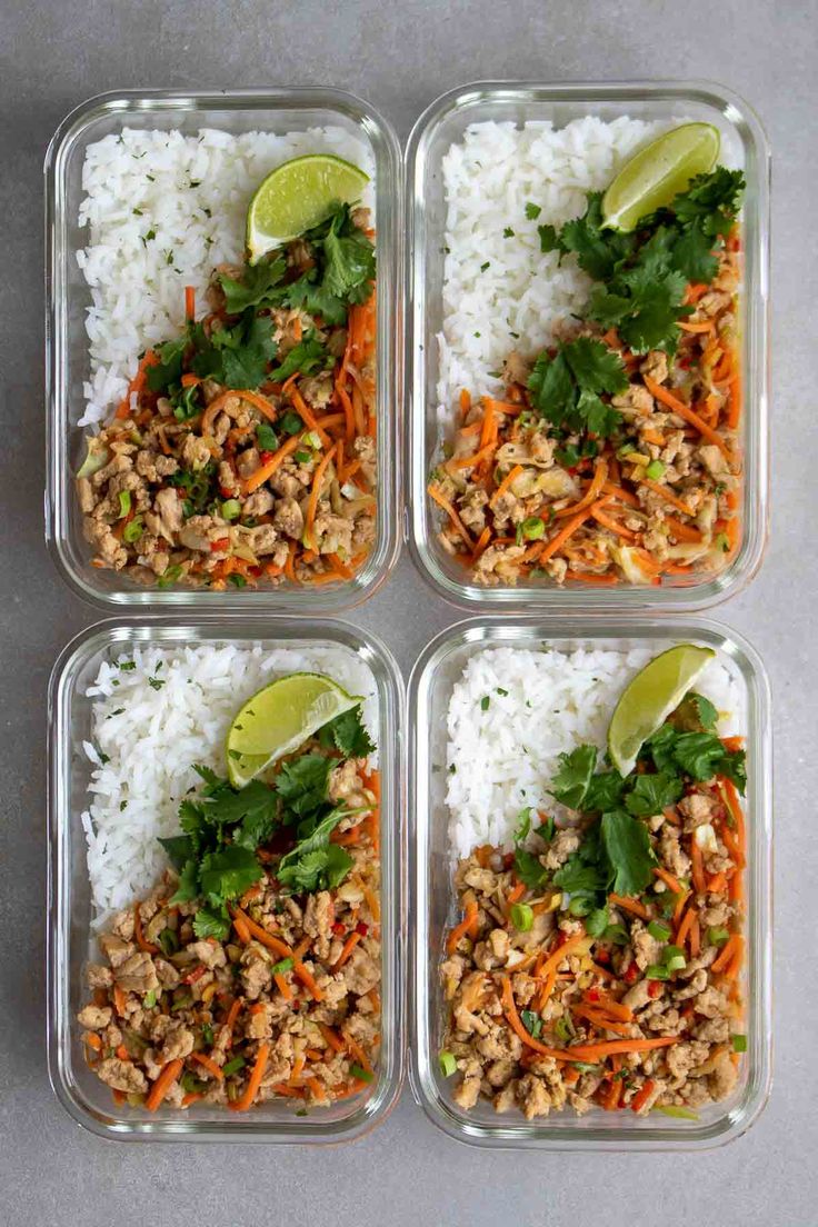 four plastic containers filled with rice and veggies next to lime wedges on the side