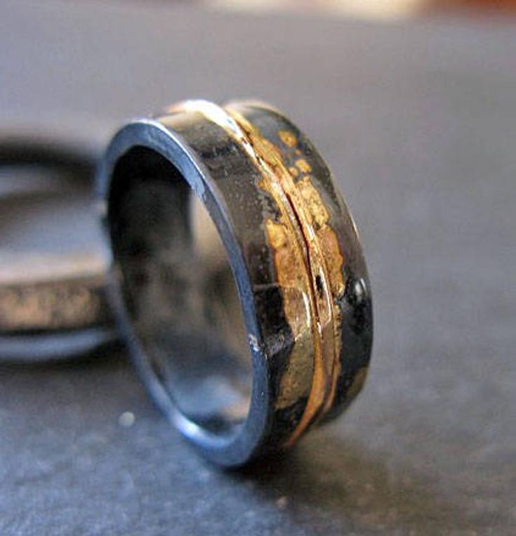 two wedding rings with gold and silver inlays sitting on top of each other