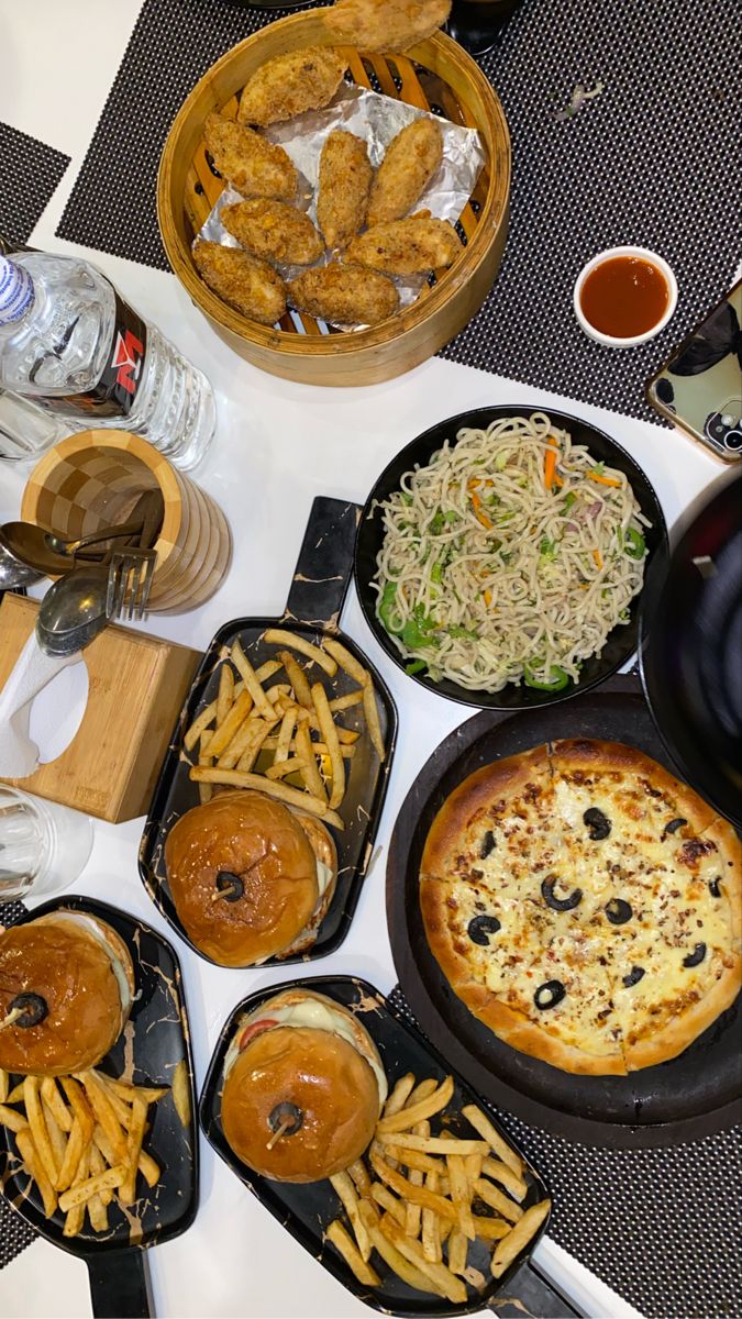 a table topped with lots of different types of pizzas and french fries on top of plates