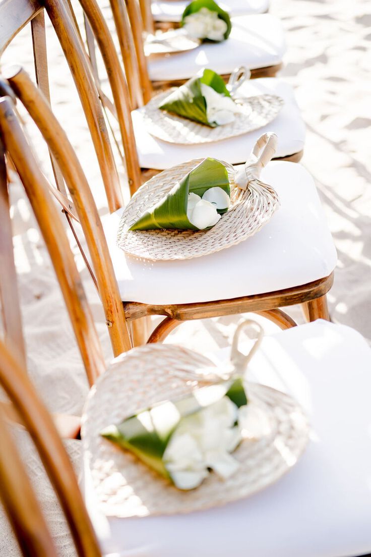 there are many plates with flowers on them sitting on the chairs at this beach wedding