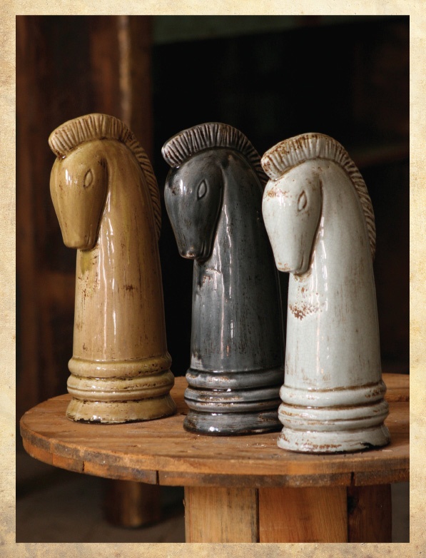 three ceramic horse heads sitting on top of a wooden table