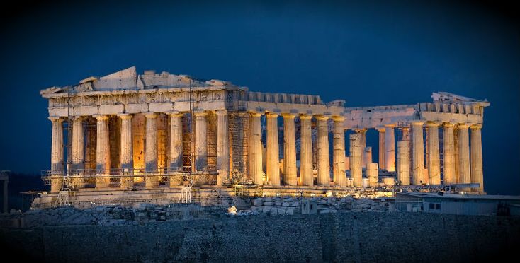 the parthenon is lit up at night with lights shining on it's sides