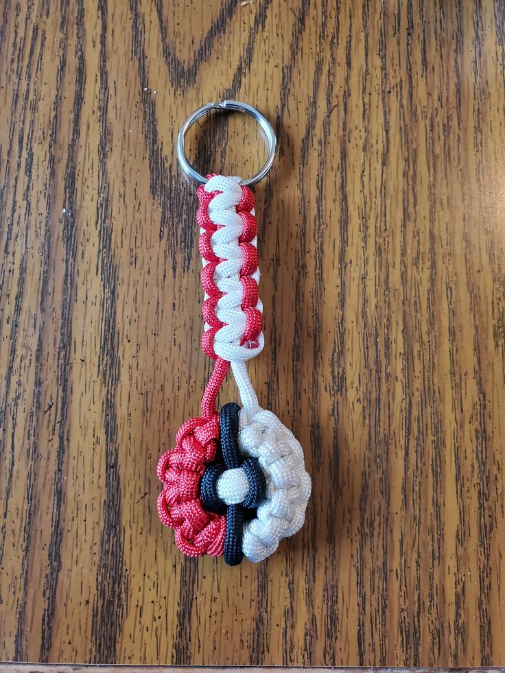 a red, white and black keychain on a wooden table