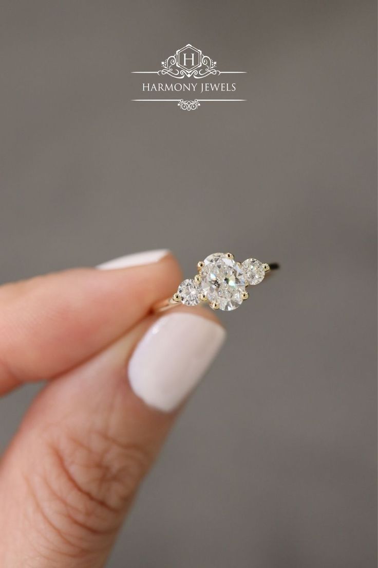 a woman's hand holding an engagement ring with two diamonds on it and the middle finger