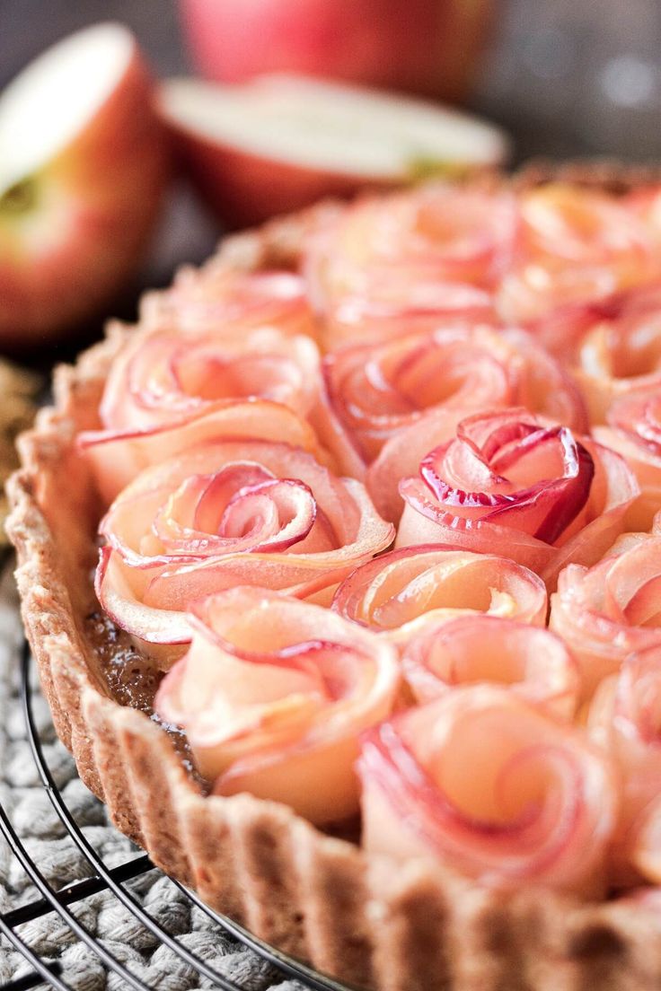 an apple tart on a cooling rack with apples in the background